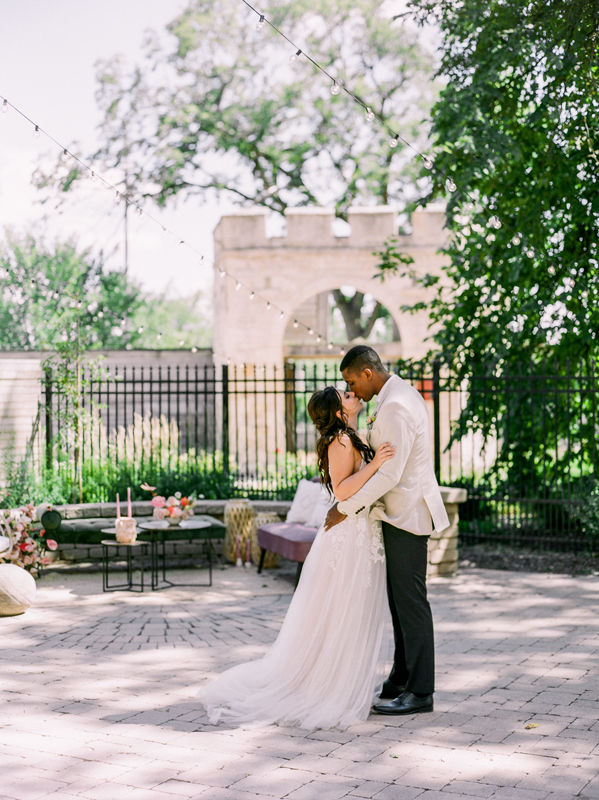 Whimsical Bonnycastle Garden wedding photo of couple kissing in front of the gates at Upper Fort Garry Provincial Park by Brittany Mahood.
